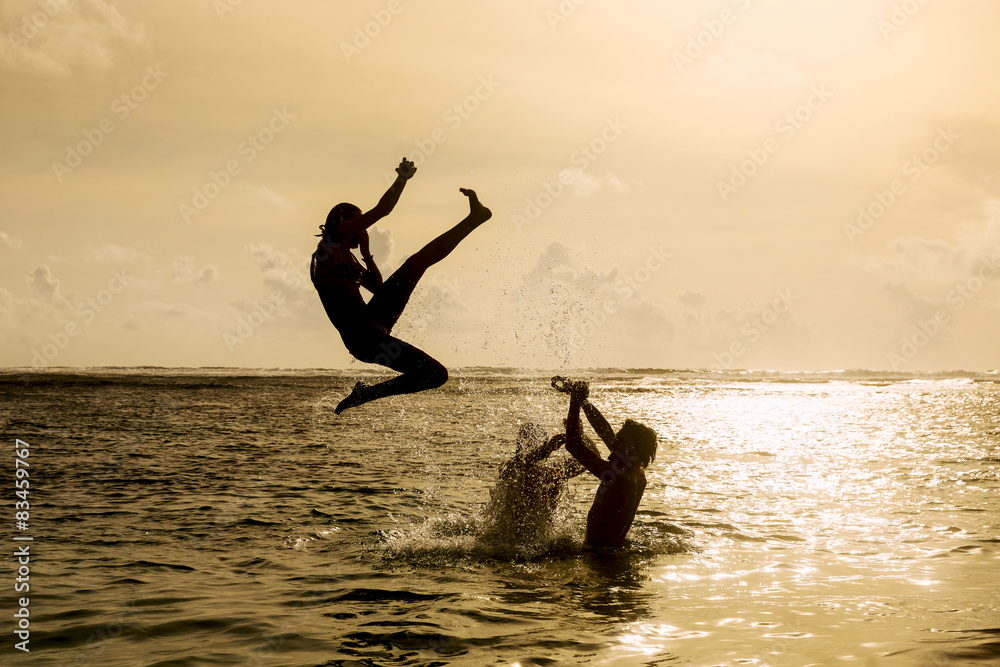 Silhouette of young woman jumping out of ocean