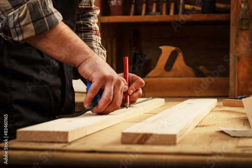 Carpenter marking a measurement on a wooden plank