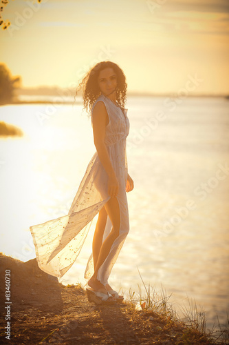 A young slender girl in a gauzy dress in the sun.  photo