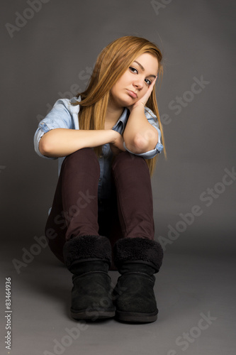 Sulky teenage girl sitting on the floor