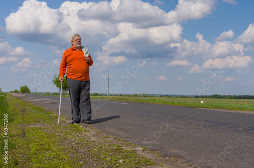 Senior man walking on the country road at sunny day