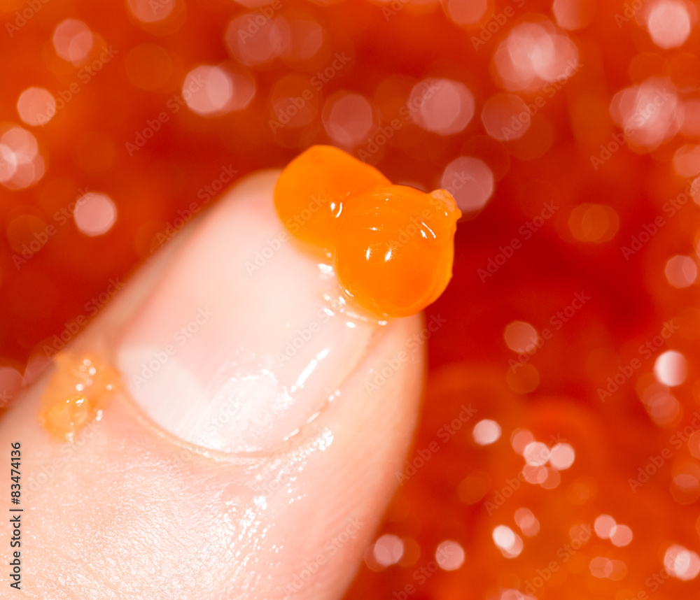 Fototapeta premium red caviar on a finger. close-up