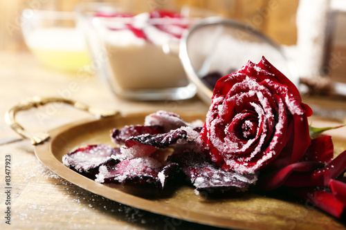 Making candied rose flower petals with egg whites and sugar, on wooden background