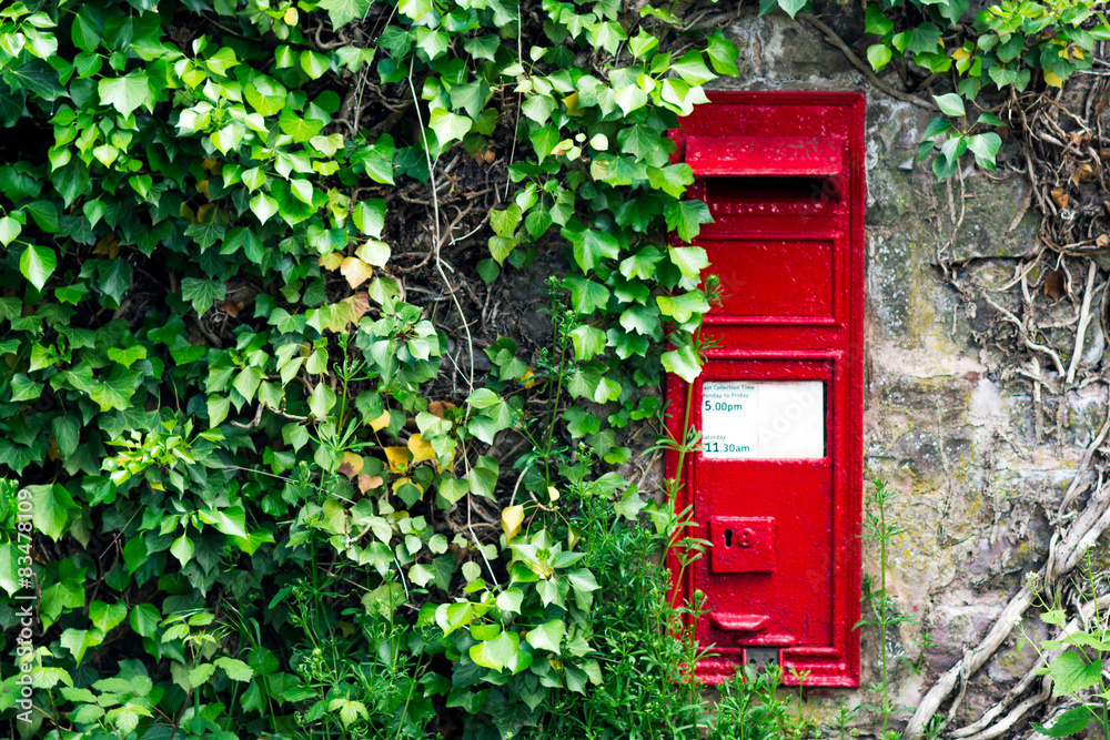 Red Post Box Mounted on a old Crumbling Wall. Overgrown Plants Red Post Box Mounted on a old Crumbling Wall. Overgrown Plants