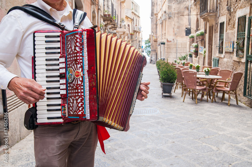 Accordion musician playing on alley of old Syracuse, Sicily, Italy