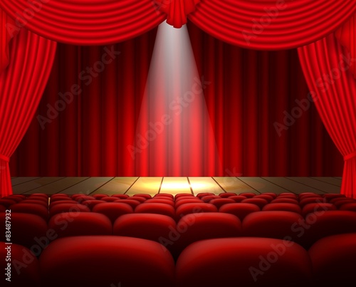 A theater stage with a red curtain, seats and a spotlight