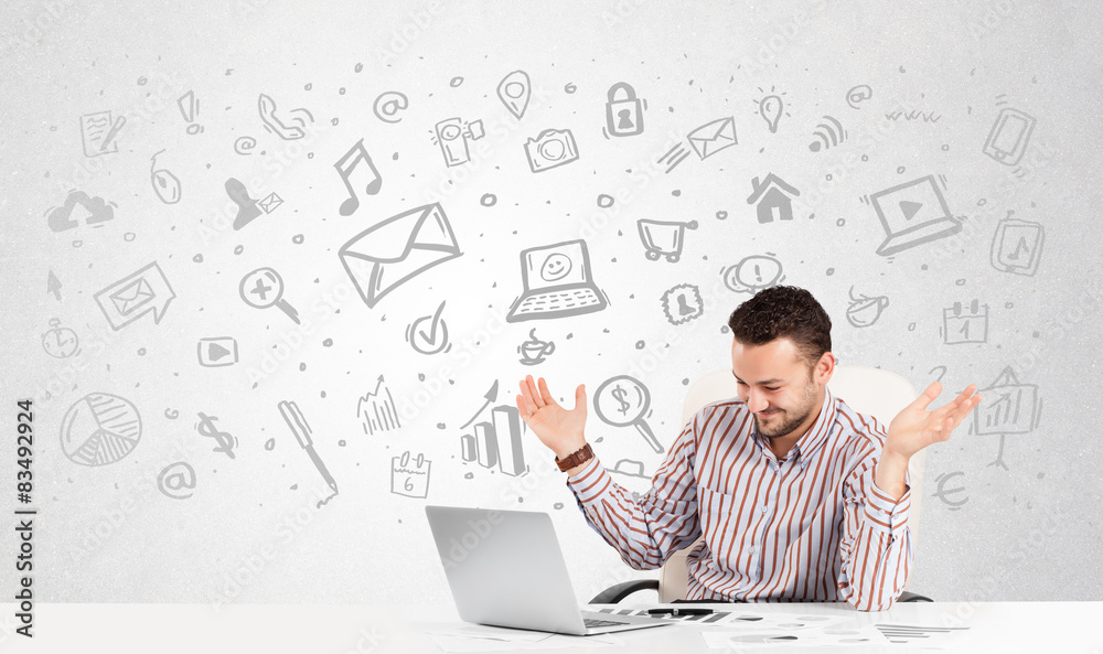 Business man sitting at table with hand drawn media icons Business man sitting at table with hand drawn media icons