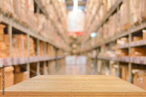 Empty wood table top (or shelf) on blurred warehouse background