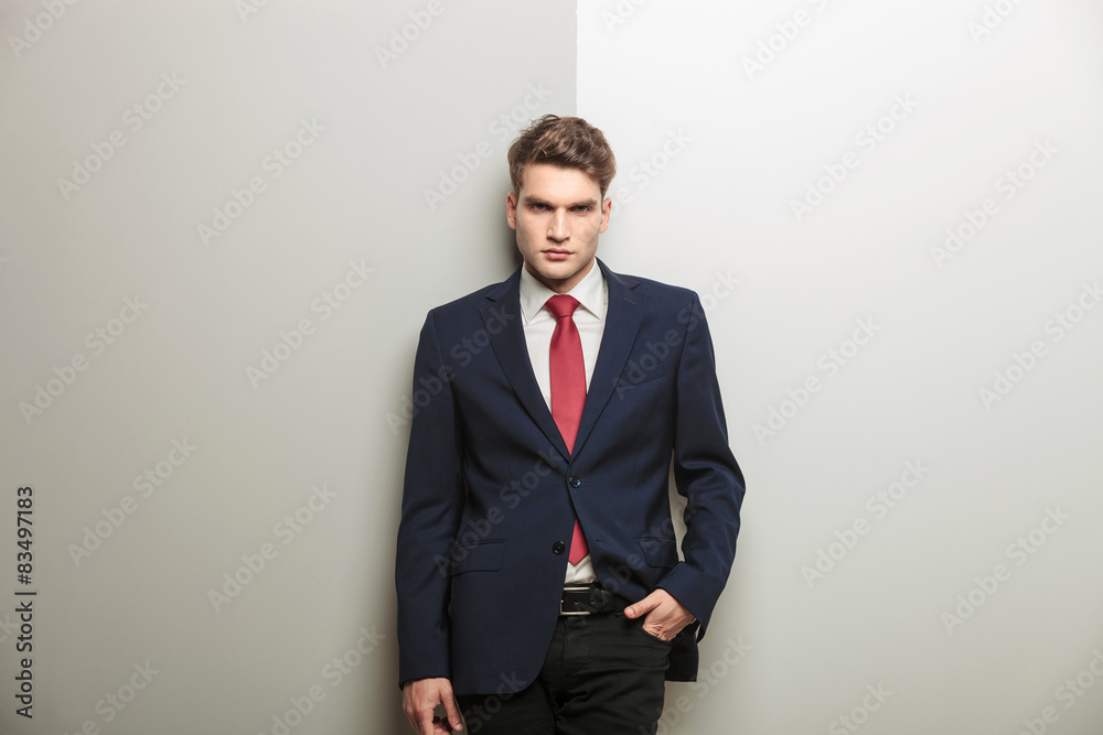 Casual young business man leaning on a grey wall. Casual young business man leaning on a grey wall.