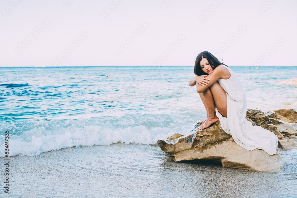 beautiful girl sitting on a rock on the beach sea Stock Photo | Adobe Stock