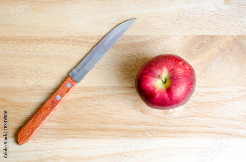 Red apple and knife on wooden table