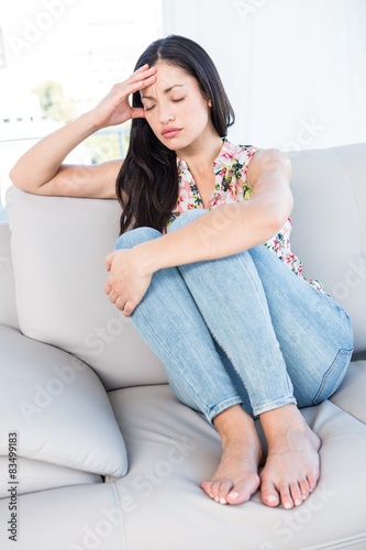 Pretty brunette with headache on couch