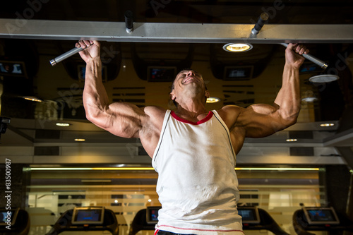 Fotografie Muscle athlete man in gym making elevations.
