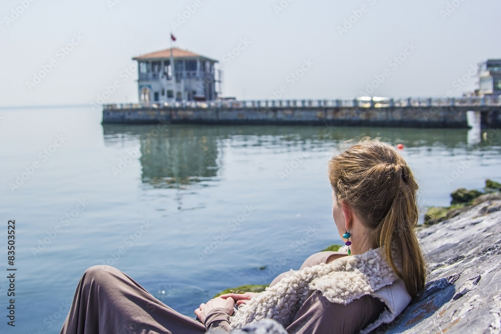 Fototapeta premium woman sitting on the rocks on the waterfront in Kadikoy