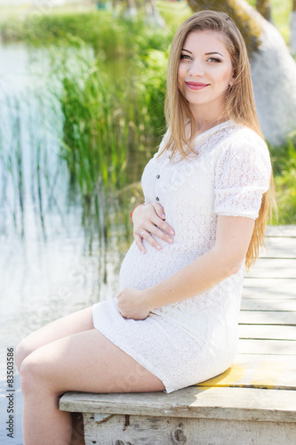 Pregnant girl sitting on bridge near river