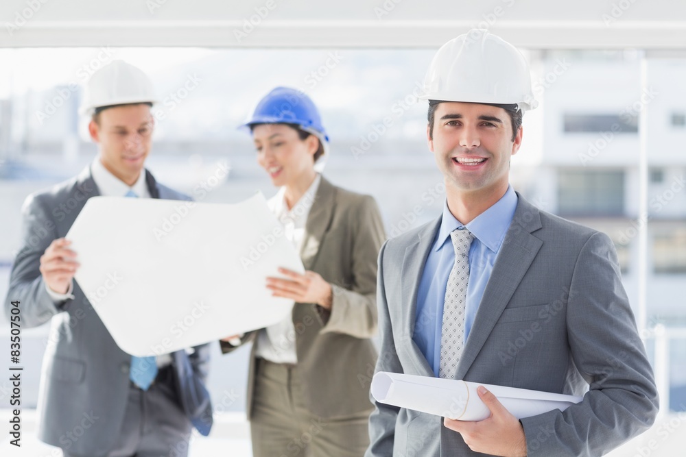 Businessmen and a woman with hard hats and holding blueprint Businessmen and a woman with hard hats and holding blueprint