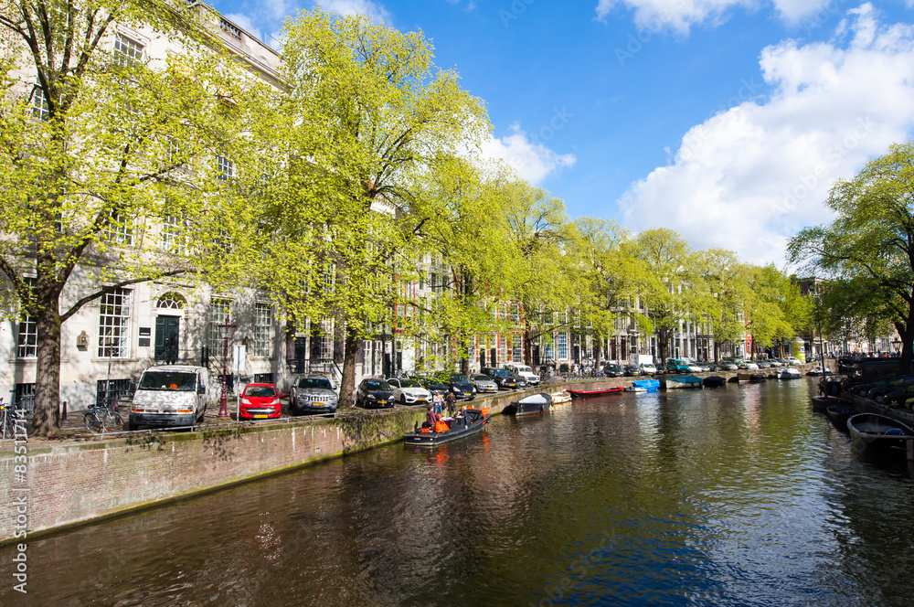 Amsterdam canal with boats along the river's bank in the spring.