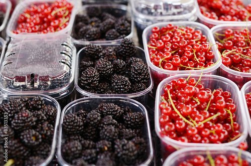 Blackberry and red currant in plastic containers at the market