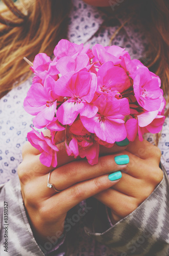Stylish lady holding bunch of pink flowers in her hands with tea