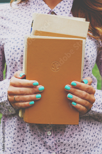 Young woman holding book pile in her hands