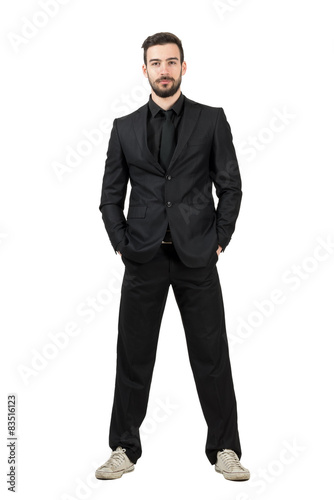 Smiling businessman with hands in pockets wearing sneakers 