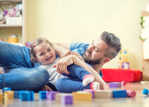 Young father spending time with his little daughter at home