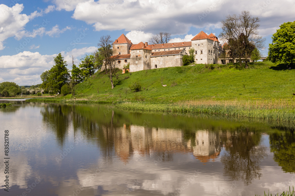old castle and green reflection in blue water with cloudy sky background