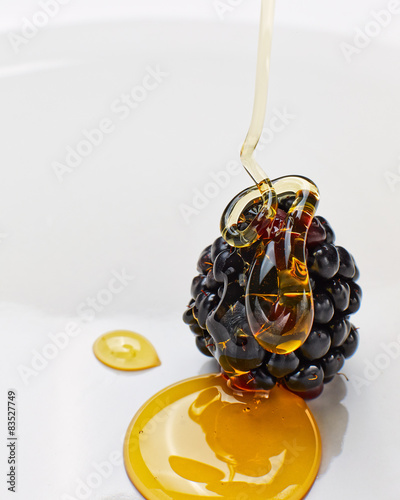 Close-up of honey being drizzled on a fresh Blackberry