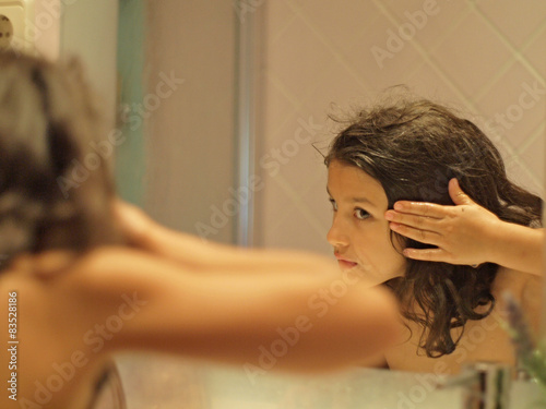 Spain, Barcelona, girl (8-9) looking at reflection in mirror, washing hair