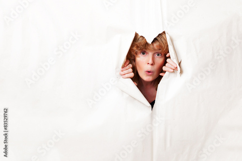 Woman looking through torn paper photo