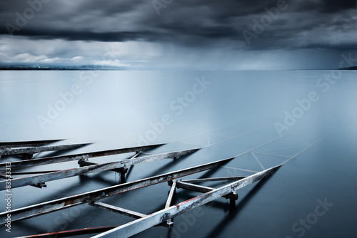 Switzerland, Vaud, Villette, Lake Leman, Slipway in still lake with storm clouds on horizon photo