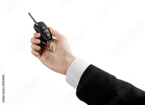 car salesman in a black suit holding a car key isolated