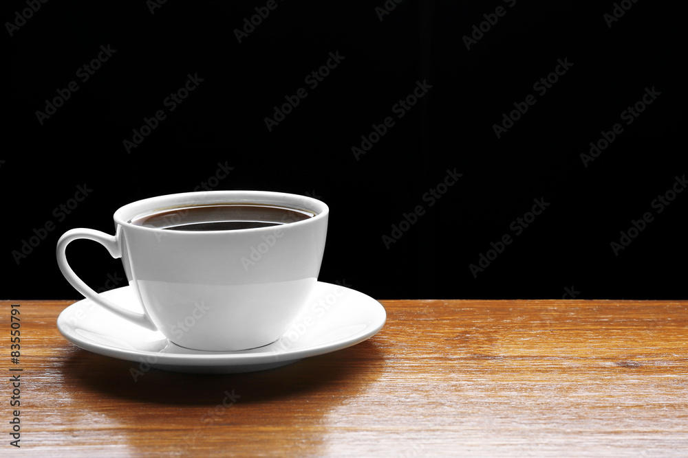 Cup of coffee on wooden table on black background Cup of coffee on wooden table on black background