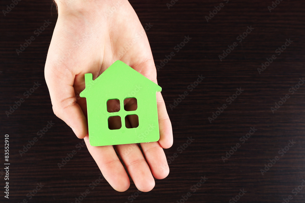 Female hand holding house on wooden background Female hand holding house on wooden background