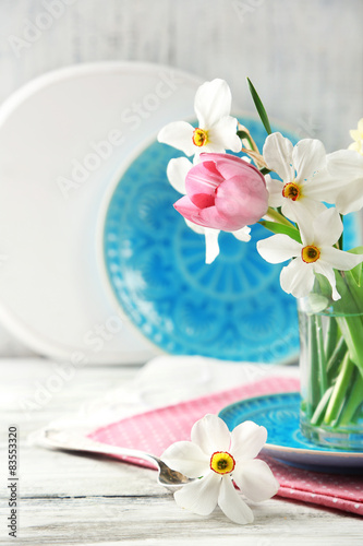Spring bouquet in glass mug on color wooden background