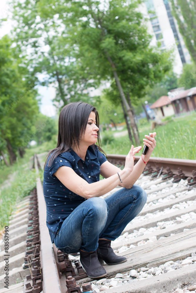 Pretty Girl Texting On Phone Along The Tracks