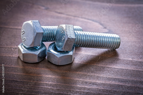 Couple of stainless bolt details and nuts on vintage brown woode