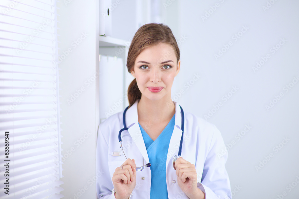 Woman doctor is standing near window with crossed arms,isolated Woman doctor is standing near window with crossed arms,isolated