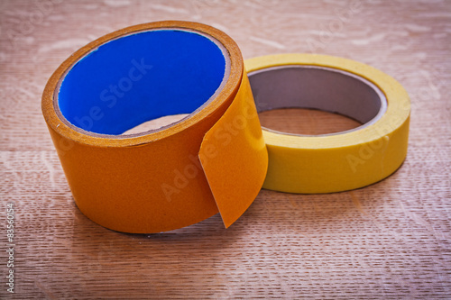 Rolls of wide and narrow duct tapes on vintage wood board mainte