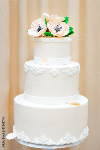 Delicious white wedding or birthday cake decorated with flowers
