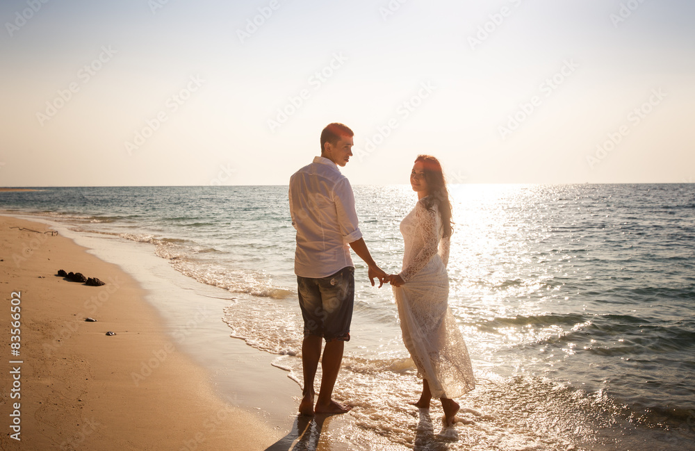 bride and groom at edge of water against sun rays