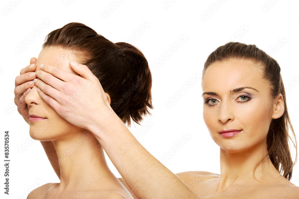 Woman covering friend's eyes.