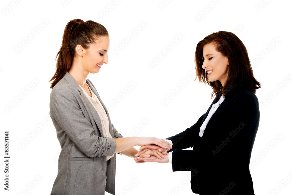 Two businesswomen holding their hands together.
