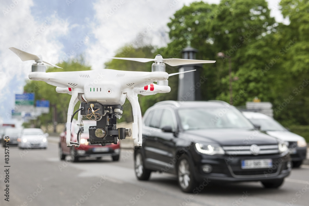 Flying drone with camera beside a road