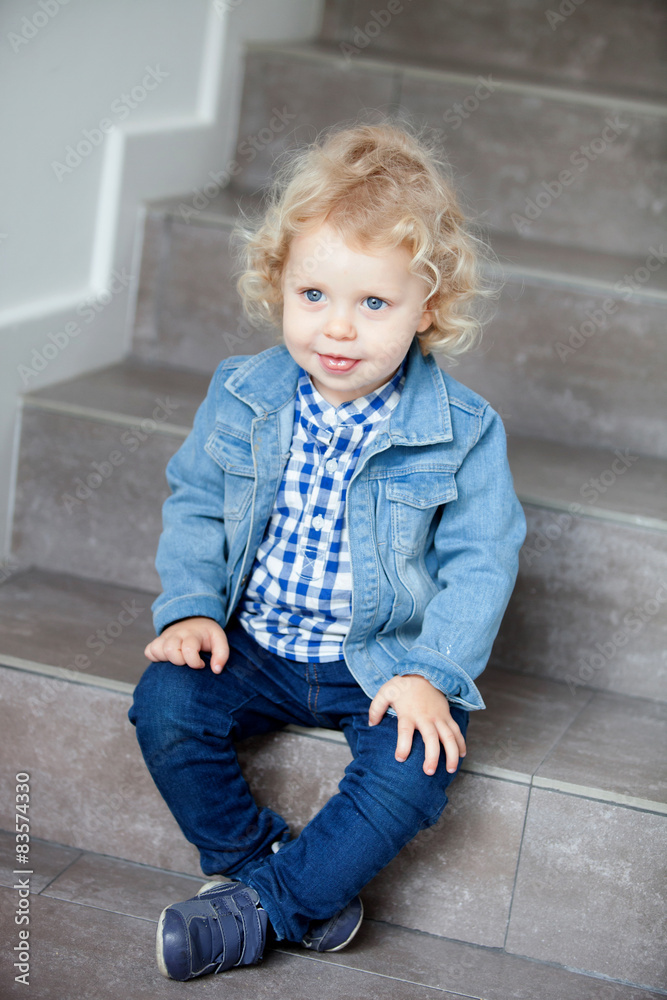 Blond baby sitting on the stairs at home Blond baby sitting on the stairs at home