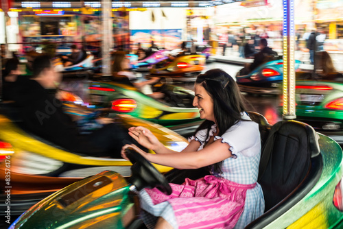 Quadro em tela Beautiful girl in an electric bumper car at amusement park