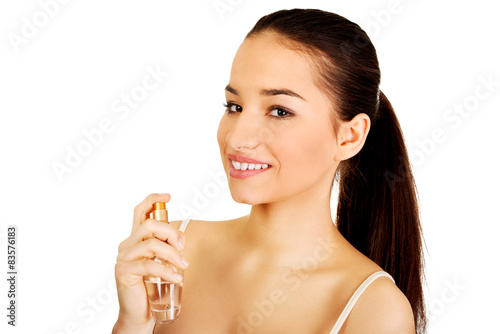 Young woman applying parfume.
