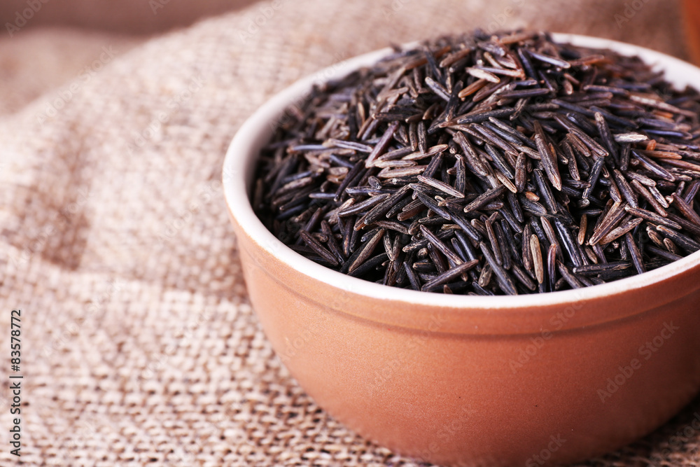 Black rice in bowl on sackcloth background Black rice in bowl on sackcloth background