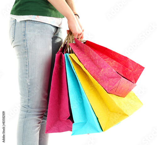 Colorful shopping paper bags in female hands isolated on white
