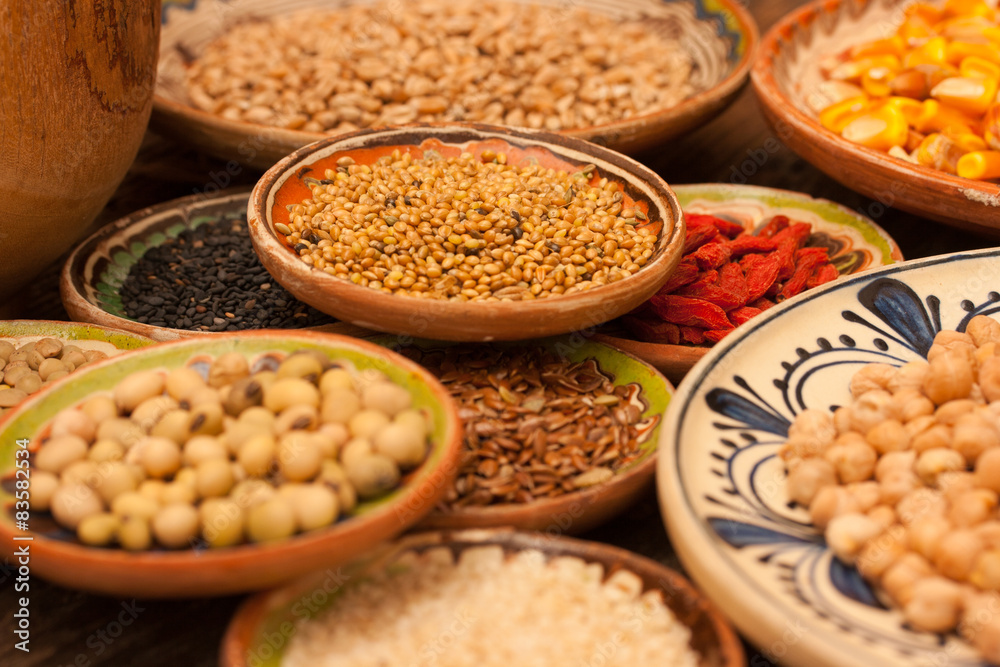 Various grain beans in small clay plates on natural textured woo